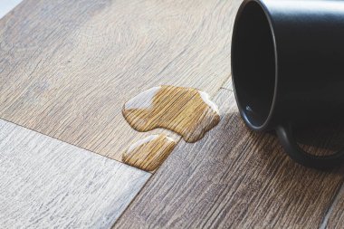 Laminat ve su. Su geçirmez kaplama. Ahşap zemin nemden etkilenmez. Zemin kaplamaları sudan korur. Yerde bir su birikintisi.
