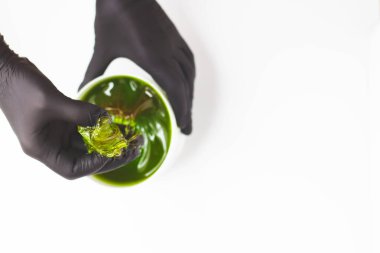 Shugaring. Elinde şeker tutkalı var. Sıcak balmumuyla saç kesimi. Şekerleme ustasının elleri. Siyah eldivenlerle..