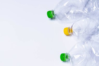 Plastik atıklar. Plastik şişeler. Atık ayıklama. Gezegeni çöpten temizlemek. Toprak temizliği. Plastik kaplardaki kapaklar sarı ve yeşildir. Kırışık plastik..