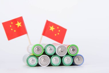 Batarya. Çin bayrağının arka planında bir sürü pil var. Alkali ve alkali pil. Çinko ve tuz bataryası. Lityum ithalatı. Çöp öğütücü.