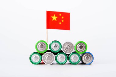Batarya. Çin bayrağının arka planında bir sürü pil var. Alkali ve alkali pil. Çinko ve tuz bataryası. Lityum ithalatı. Çöp öğütücü.