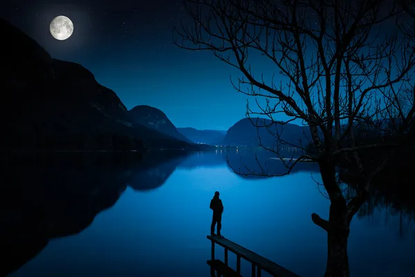 Uomo in piedi vicino al lago, coperto di chiaro di luna — Foto Stock