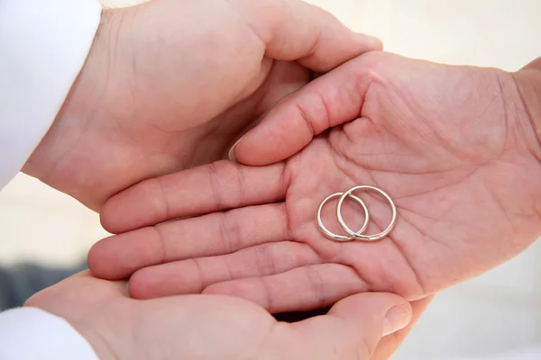 Palmas segurando anéis de casamento — Fotografia de Stock