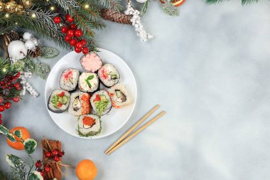 Hafif bir arka planda soslu taze suşi ruloları, Noel süsleri, yeni yıl yemeği, geleneksel Japon mutfağı, dükkan reklamı veya davetiyesi için pankart, seçici odaklanma.