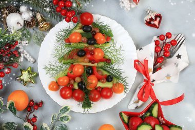 Yılbaşı yemekleri, geleneksel ringa balığı salatası, yılın sembolü, domateslerden, biberlerden, zeytinlerden, salatalıklardan, salatalıklardan ve otlardan hazırlanan vejetaryen gıda tasarımı fikri, köknar dalları ve dekorasyonlar, düz konum, seçici odaklanma