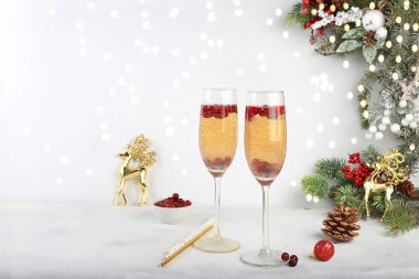 Kızılcık ve tarçın aromalı Noel alkollü kokteyli, şampanyalı Mimosa kokteyli, soğuk mevsimde ısınan kış içeceği, Noel şenlikli içki, kış kompozisyonu, seçici odaklanma.
