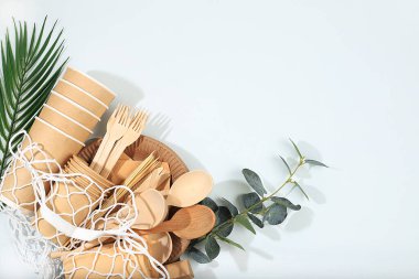 Güneşli bir masada, bir torba içinde, çevre dostu yemekler. Kağıt bardaklar, tabaklar, kağıt peçeteler, barbekü pipetleri, tahta çatallar, kaşıklar ve bıçaklar, maket, sağlıklı yaşam tarzı konsepti, sıfır atık. Plastik yok, seçici odaklanma