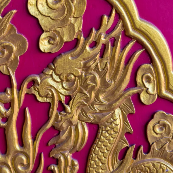Cabeza de dragón dorado en puerta de madera roja — Foto de Stock