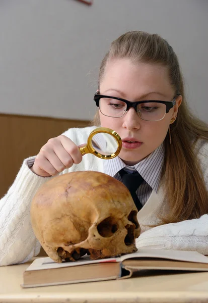 Frau untersucht menschlichen Schädel — Stockfoto