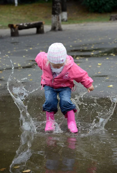 Girl jumping in puddles — Stock Photo, Image