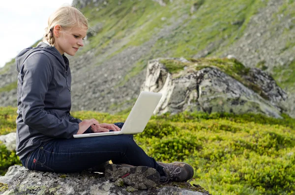 Jeune femme blonde s'assoit avec un ordinateur portable sur une pierre — Photo