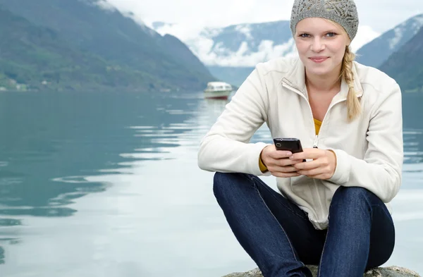 Jonge blonde vrouw met haar smartphone in de hand Rechtenvrije Stockfoto's