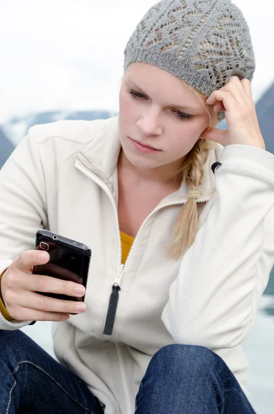Mają młode blond kobieta z jej smartphone w ręku Obrazek Stockowy