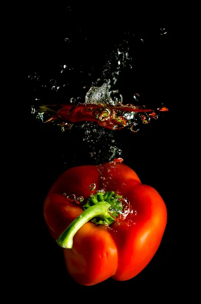 Red pepper falls in the water — Stock Photo, Image
