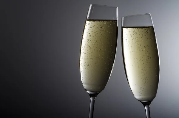 Twee champagneglazen voordat grijze achtergrond — Stockfoto