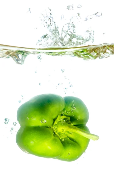Green paprika pepper splashes into water before white — Stock Photo, Image