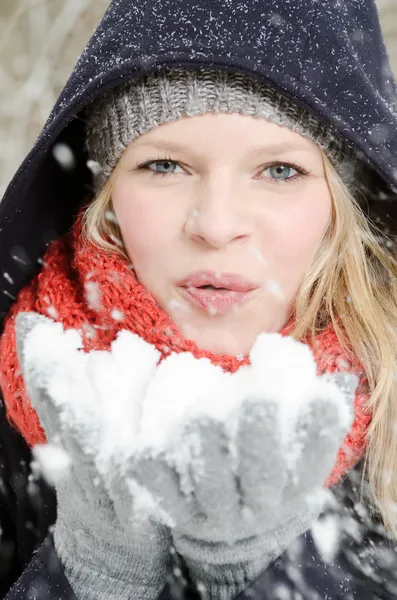 Ung blond kvinna blåser i en handfull snö — Stockfoto