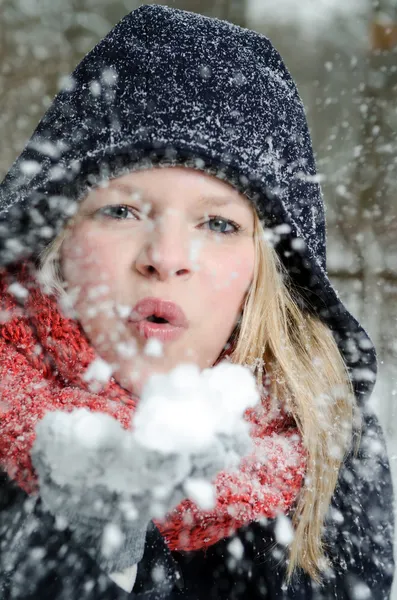 Jeune femme blonde souffle dans une poignée de neige — Photo