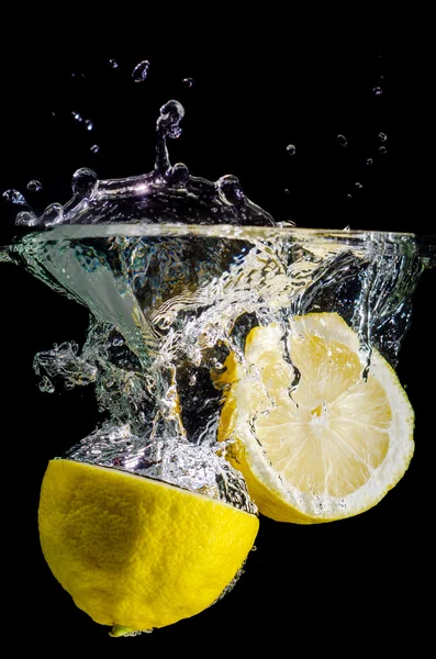 Två halverade citroner plask i vattnet — Stockfoto