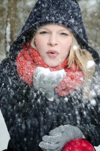 Jeune femme blonde souffle dans une poignée de neige — Photo