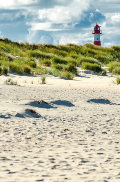 lighthouse behind beach and dunes