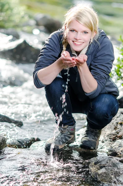 Una joven rubia senderista se refresca en un arroyo — Foto de Stock