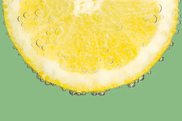 Fatia de limão com bolhas no verde fresco — Fotografia de Stock
