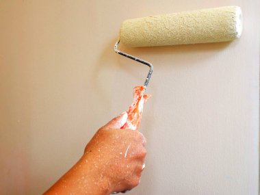 Female Hand painting the wall with paint roller. Home renovating with color