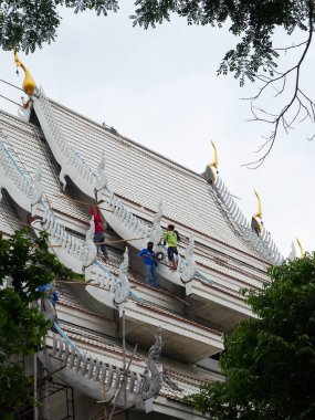 Bazı erkek işçiler tapınağın çatısını takım çalışması konsepti olarak onarıyor. Nakhon Pathom, Tayland, 8 Mayıs 2022.