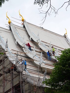 Bazı erkek işçiler tapınağın çatısını takım çalışması konsepti olarak onarıyor. Nakhon Pathom, Tayland, 8 Mayıs 2022.