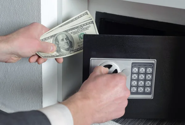 Man puts money in the safe — Stock Photo, Image