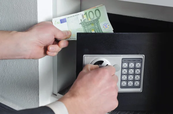 Man puts money in the safe — Stock Photo, Image