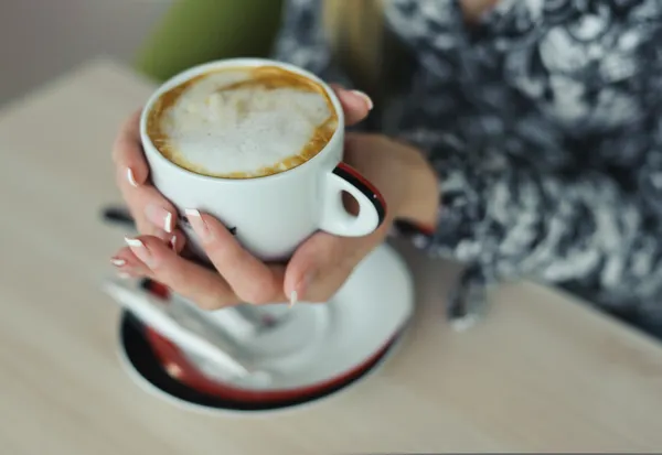 Cappuccino met in gemanicuurde handen van vrouw — Stockfoto