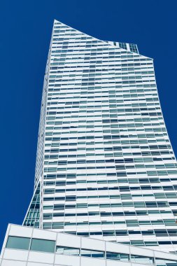 Modern mimarinin cam gökdeleni. Mavi gökyüzünün arka planına karşı eğri şekilli bir ofis binası. Alt görünüm.