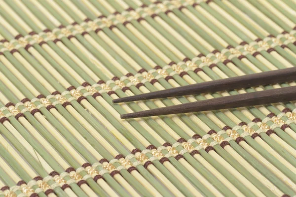Tmavé dřevěné hůlky bambusové rohože — Stock fotografie