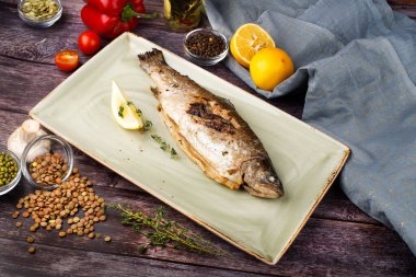 Levrek, ahşap bir masanın arka planında limonla servis edilir.