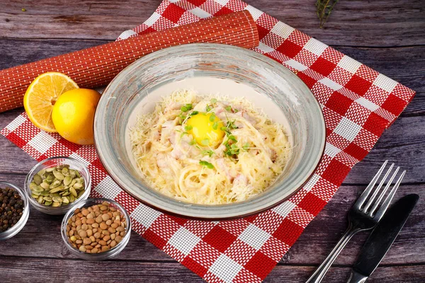 Traditional Italian pasta dish, spaghetti carbonara with yolk, parmesan cheese, bacon in plate on black rustic stone background, top view. Italian dinner with pasta