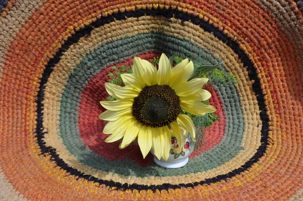 Sunflower against a round rug. — Stock Photo, Image