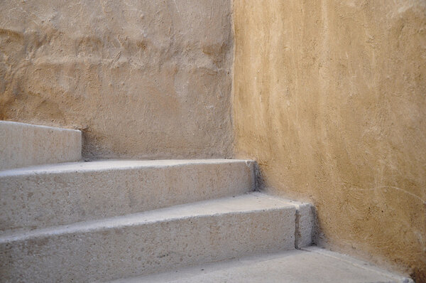 Old stone staircase with yellow stucco wall.