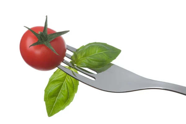 Tomaat en basilicum op een vork op wit — Stockfoto
