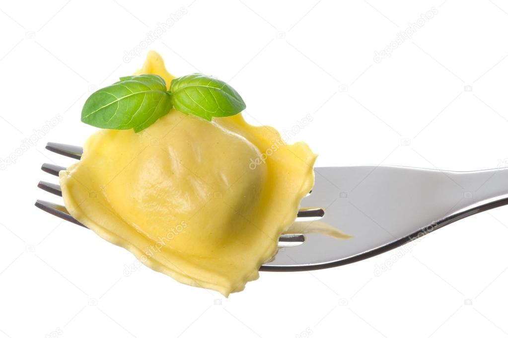 Ravioli pasta parcel and basil garnish on fork white background