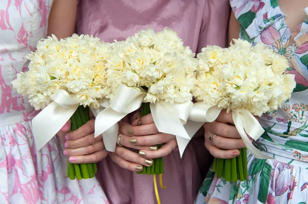 Drie narcissen bruiloft boeketten gehouden door bruidsmeisjes — Stockfoto