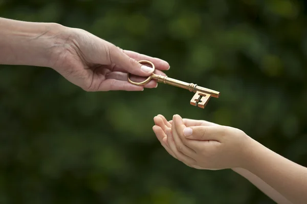 Erwachsener übergibt Schlüssel an Kind — Stockfoto