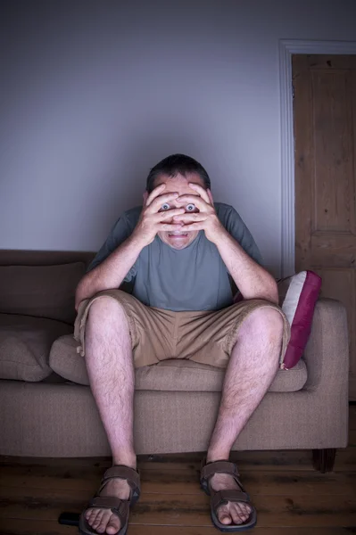 TV izlerken yüzünü kaplayan adam — Stok fotoğraf