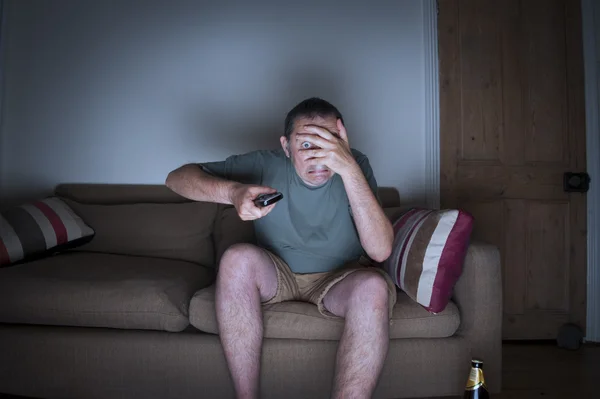 Hombre cubriendo cara viendo tv — Foto de Stock