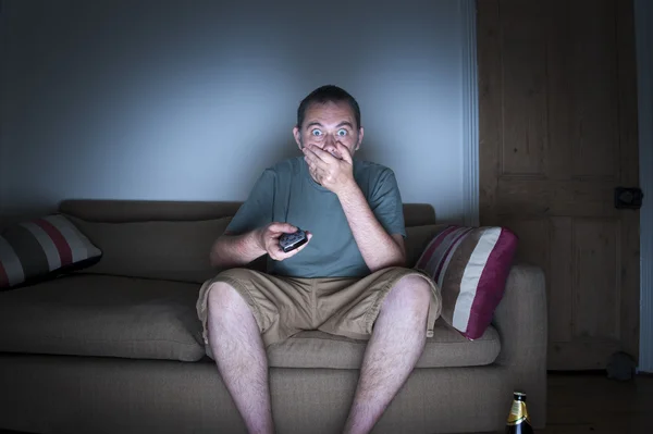 Man covering mouth watching tv — Stock Photo, Image