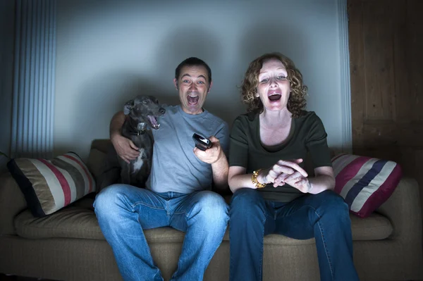 Pareja de mediana edad y perro riendo de la televisión — Foto de Stock