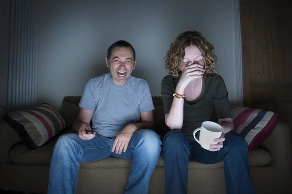 Couple watching television laughing and embarrassed — Stock Photo, Image