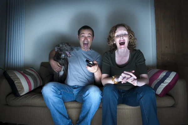 Middle aged couple and dog laughing at the television — Stock Photo, Image