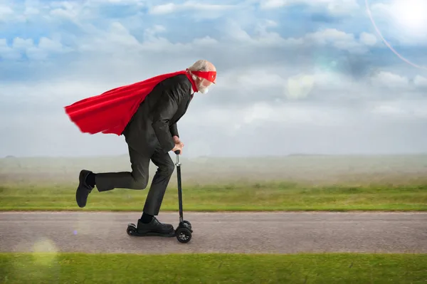 Senior superhero riding a scooter — Stock Photo, Image